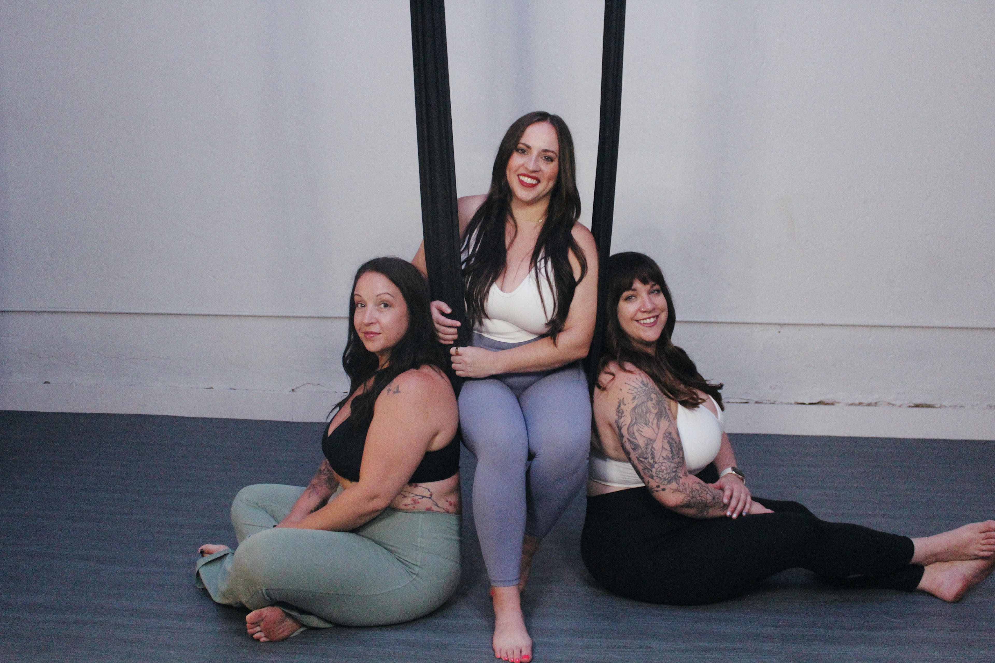 Three women sitting on the floor in a yoga studio setting, with the most supportive bras for movement and everyday wear.
