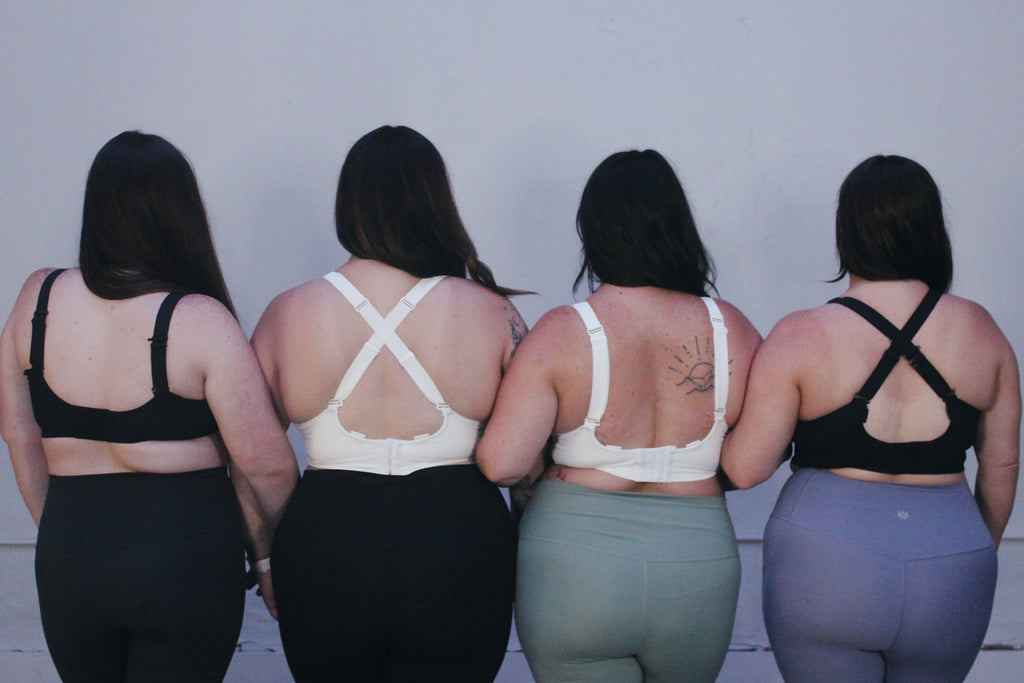 Four women wearing medium to high support bras for short torsos but full cups, in a range of sizes H cup to G cup.