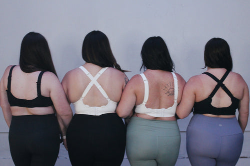 Four women wearing medium to high support bras for short torsos but full cups, in a range of sizes H cup to G cup.